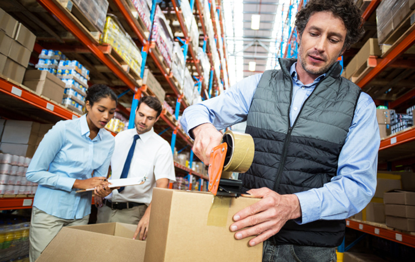 un manutentionnaire dans un entrepôt ferme un carton