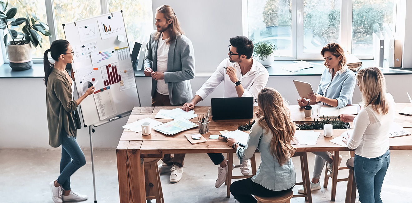 Une équipe dans un bureau échange autour d'une table et d'un ordinateur